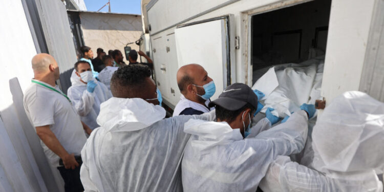 Morgue workers unload the bodies of Palestinians that had been in Israeli custody, after they were transported by Red Crescent vehicles and refrigerated trucks, to the Nasser hospital in Khan Yunis in the southern Gaza Strip on October 15, 2025. Under the ceasefire deal brokered by the US president, Israel was to turn over the bodies of 15 Palestinians for every deceased Israeli returned. (Photo by Omar AL-QATTAA / AFP)